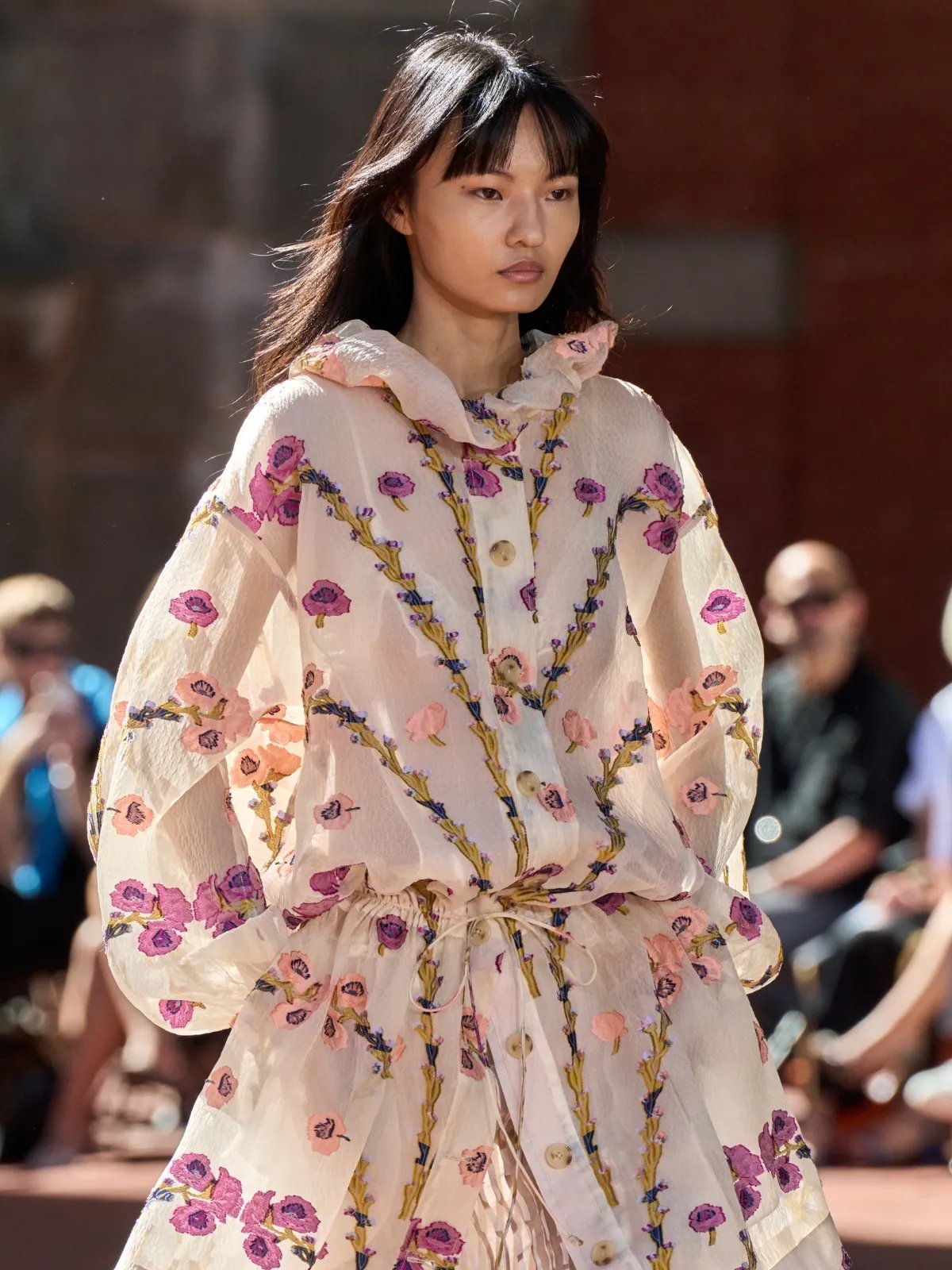 Model with long, glossy, dark brown hair, wearing a floral dress on the Ulla Johnson runway.
