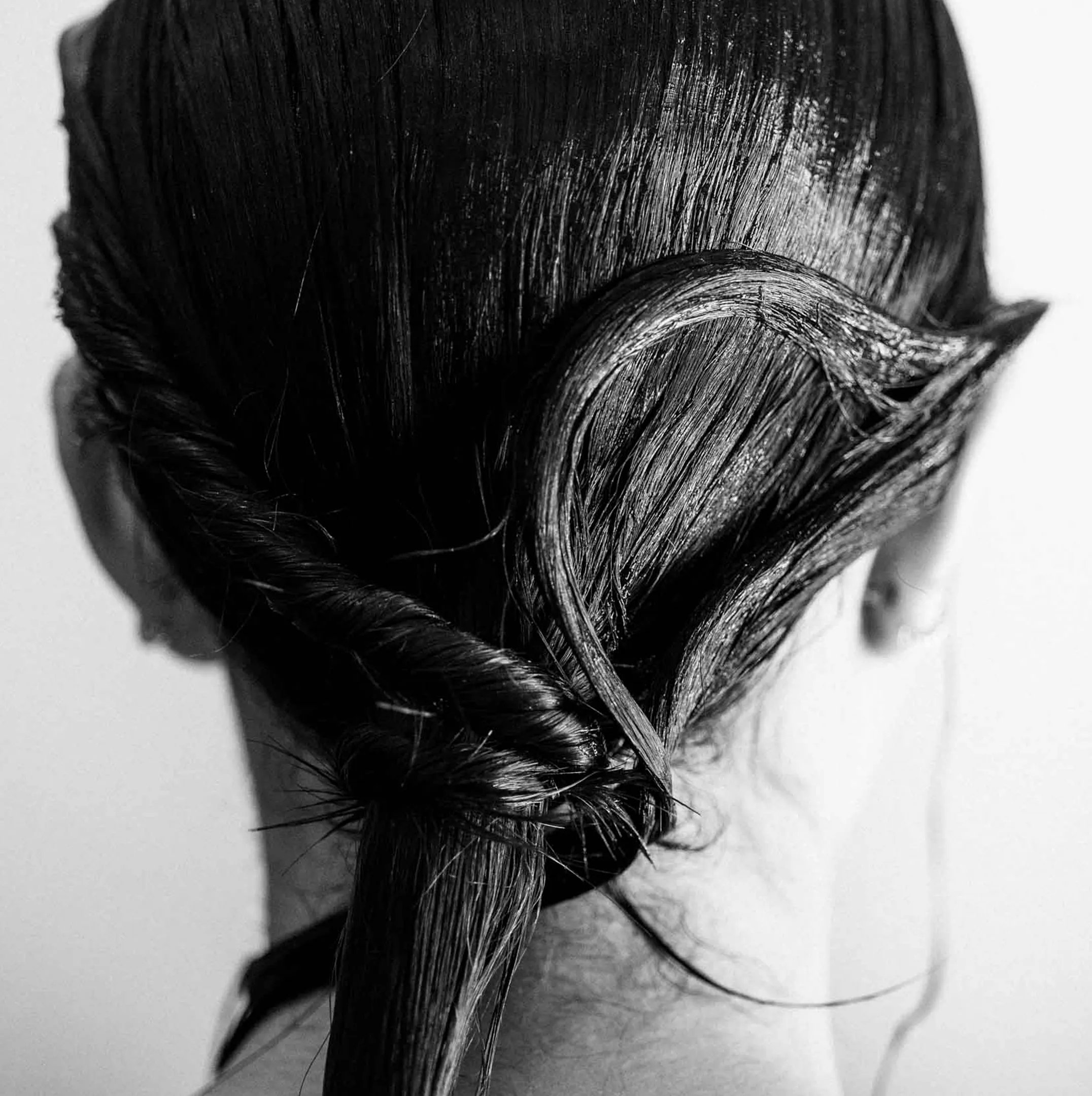 Veduta aerea di una modella con capelli rossi e acconciati, che indossa un blazer nero, su sfondo bianco. 