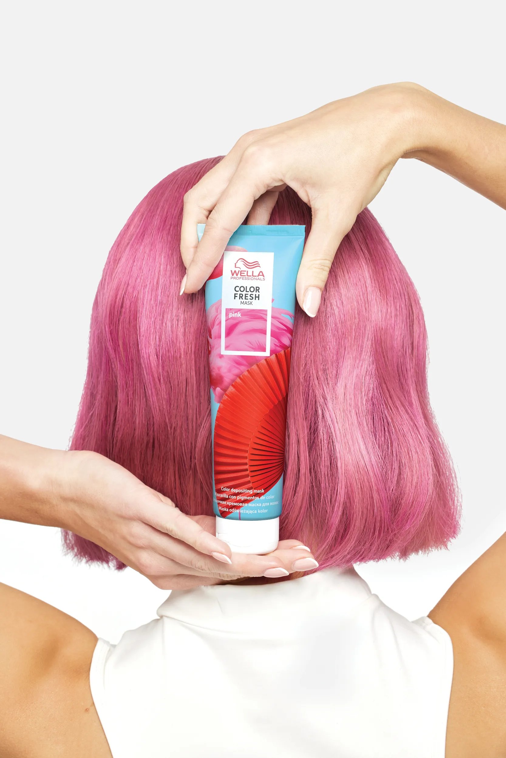 Rückansicht vom Kopf einer Frau, die eine Color Fresh Mask in der Hand hält.