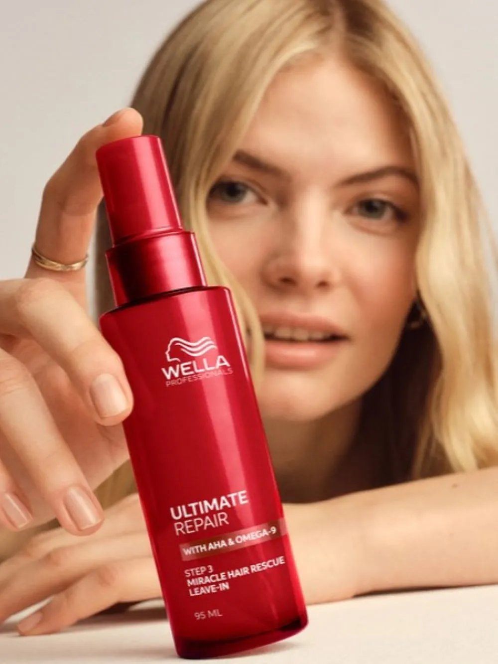 Model holding a Wella Professionals Ultimate Repair leave-in treatment bottle