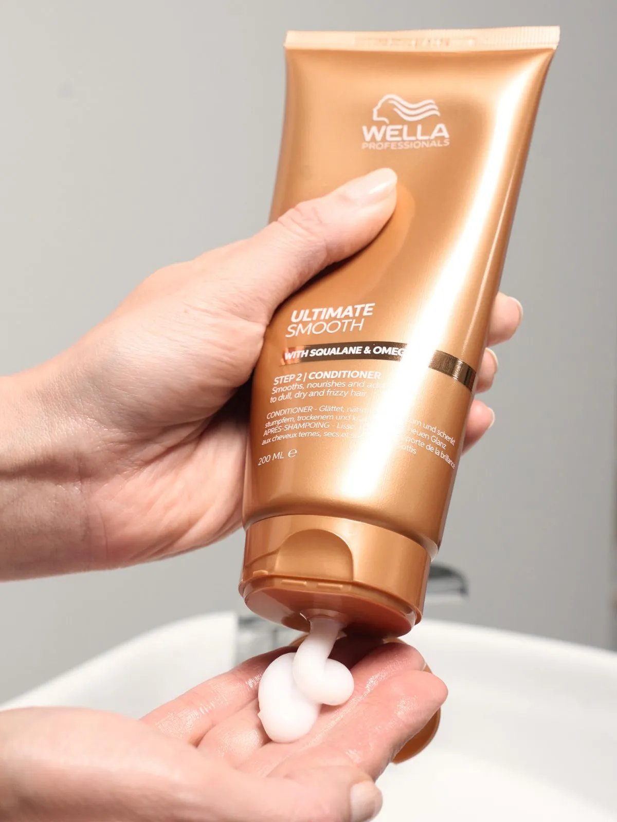 Model squeeze ULTIMATE SMOOTH Conditioner into palm of hand.