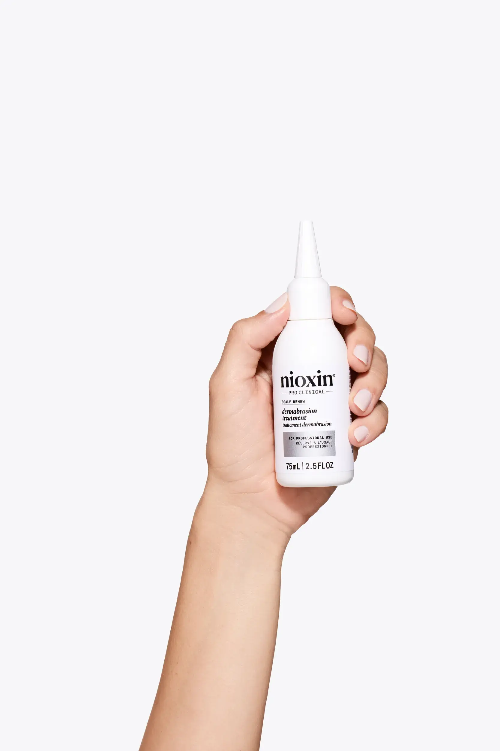 Tratamiento Dermabrasion de Nioxin en una mano sobre fondo blanco