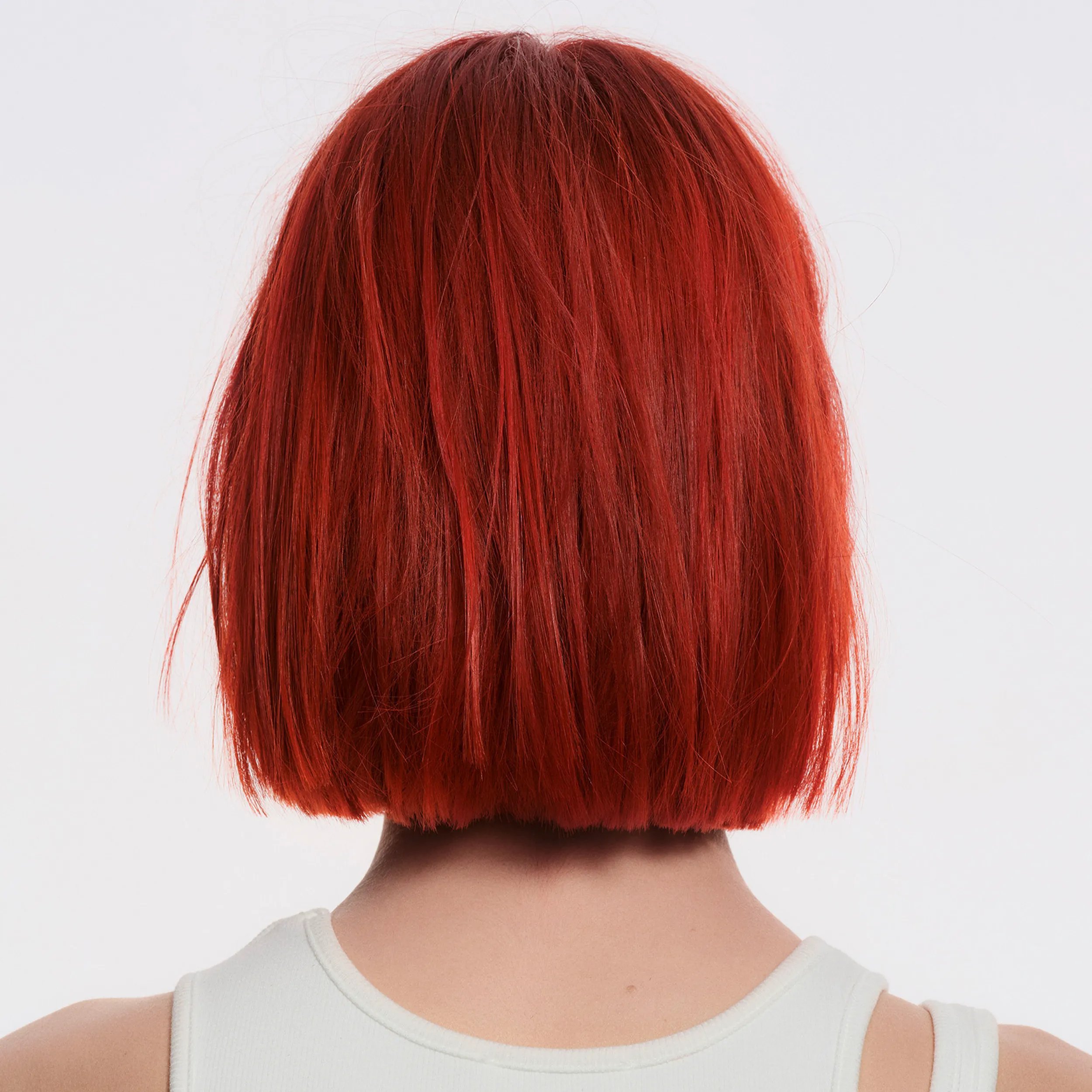 Image of the back of a model's head against a white background. Hair is short, red and slightly frizzy. 	