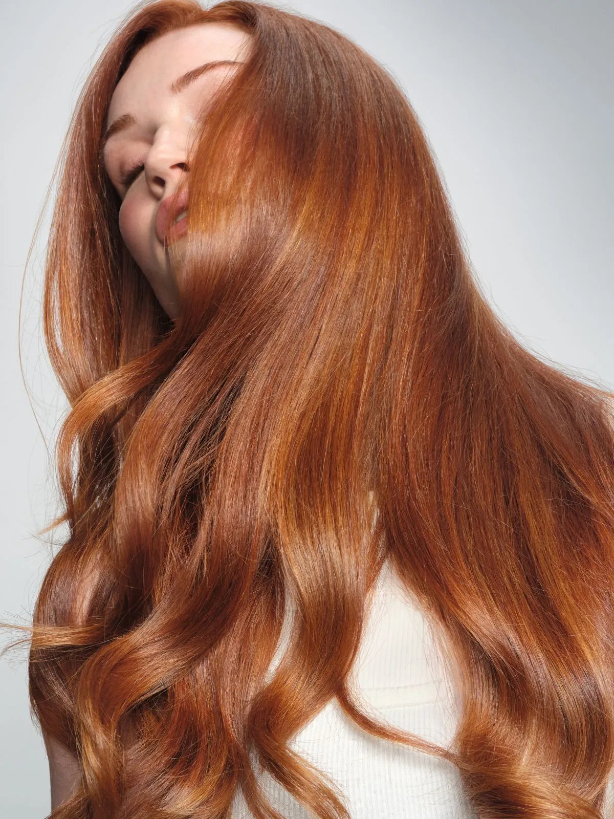 Model with long, glossy, vibrant copper hair.