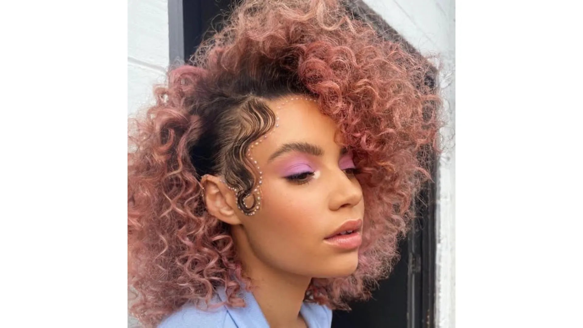 Model with dark, curly hair featuring dusty pink tones through the lengths.