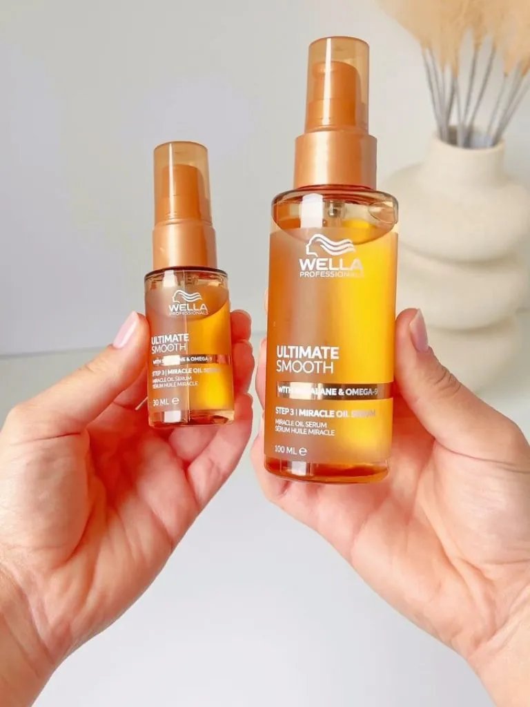 Model holds up mini and full-size bottles of ULTIMATE SMOOTH Miracle Oil Serum.