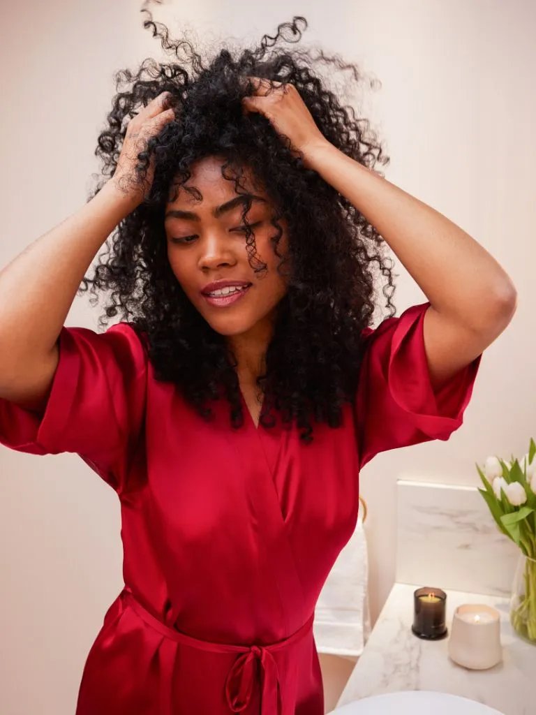 Model smooths ULTIMATE REPAIR Night Serum through their curly hair.