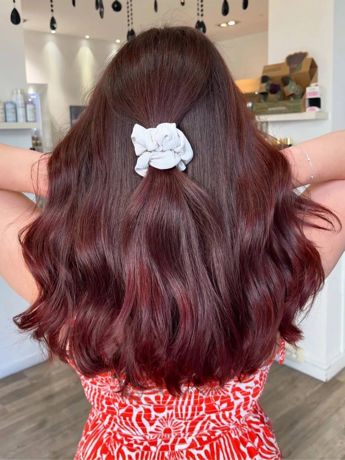 Model with loosely curled maroon hair featuring hints of plum through the ends.