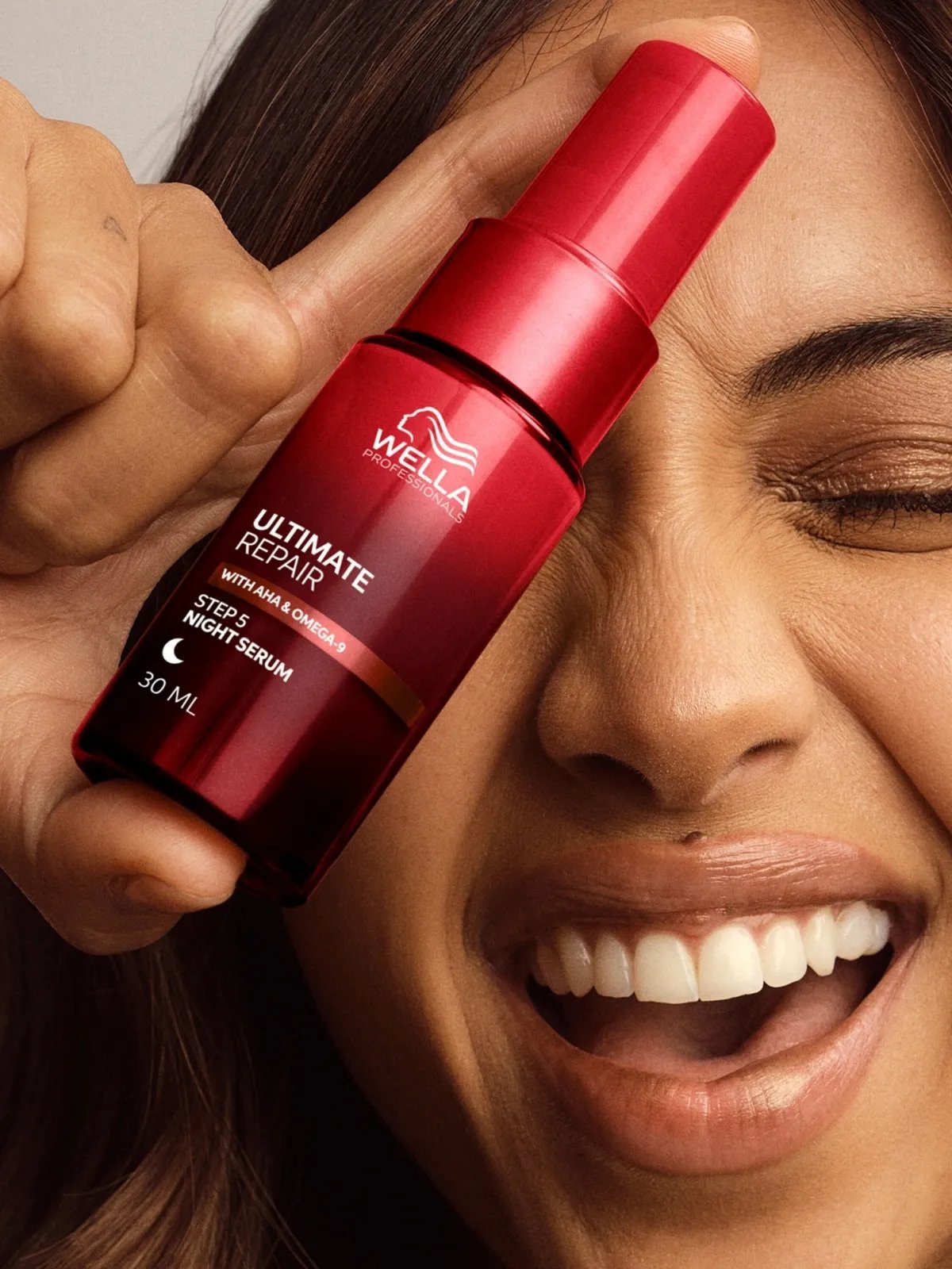 Model holds ULTIMATE REPAIR Night Serum in front of face.