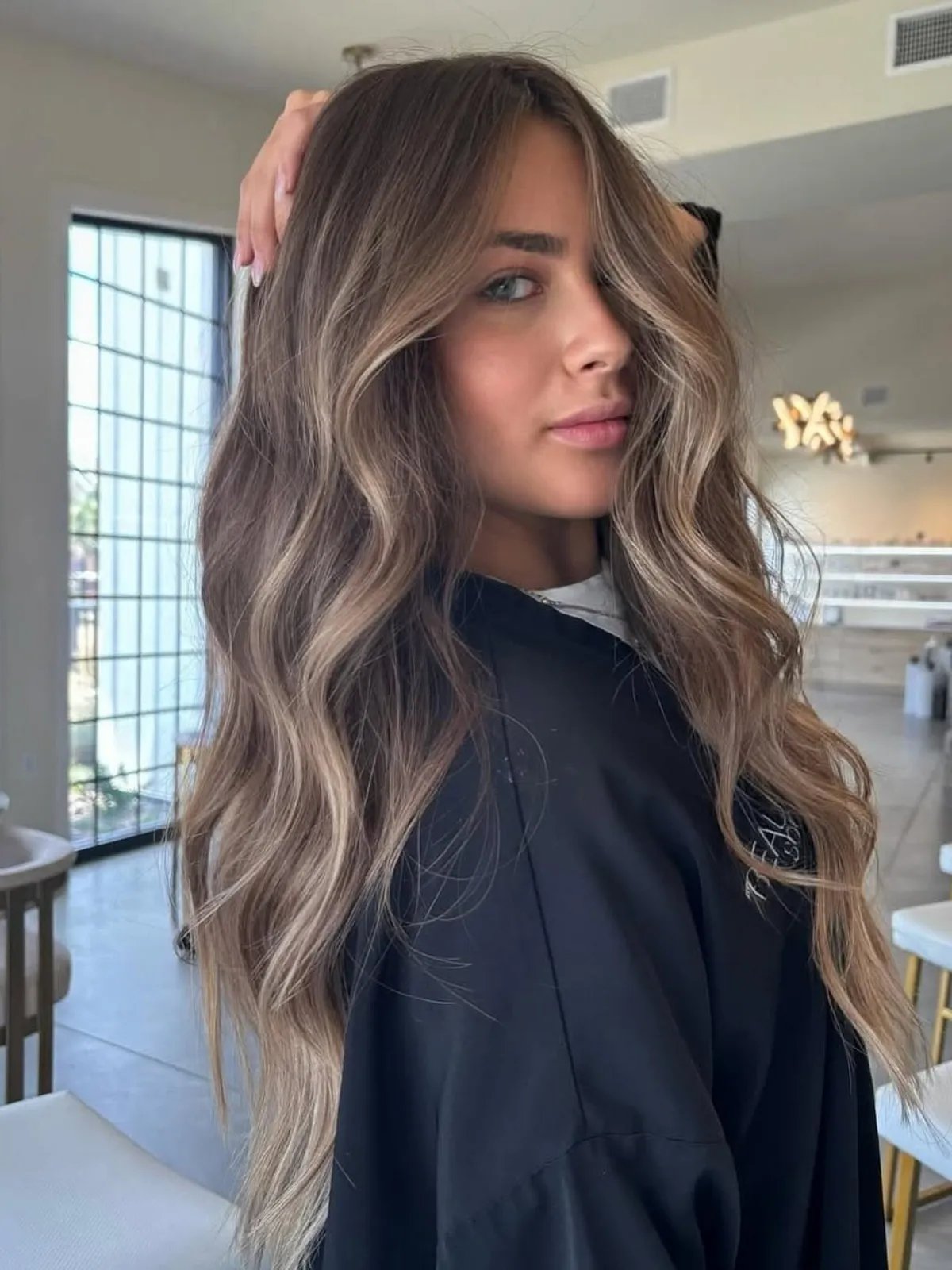Model with dark blonde, wavy hair featuring a subtle beige blonde balayage.