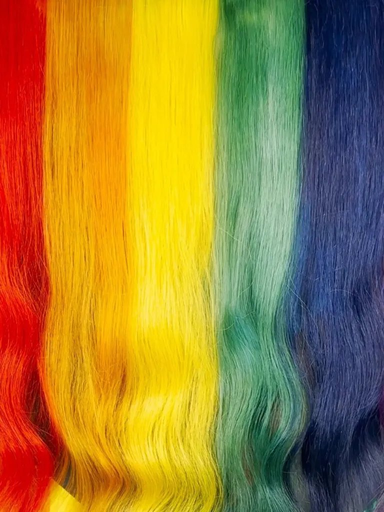 A close-up of a model’s rainbow hair, representing the original Pride flag.
