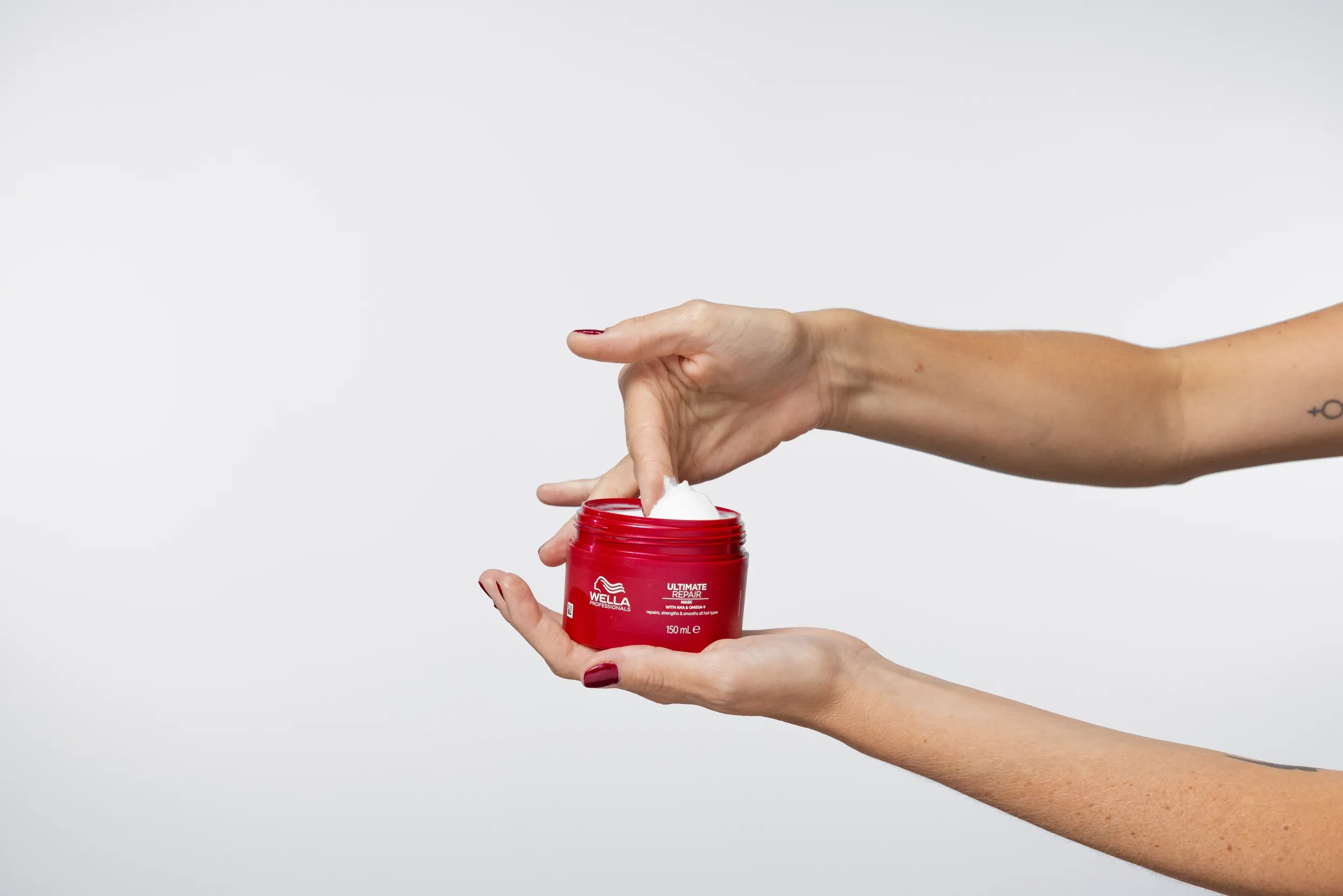 Model scoops the ULTIMATE REPAIR Mask out of the jar.