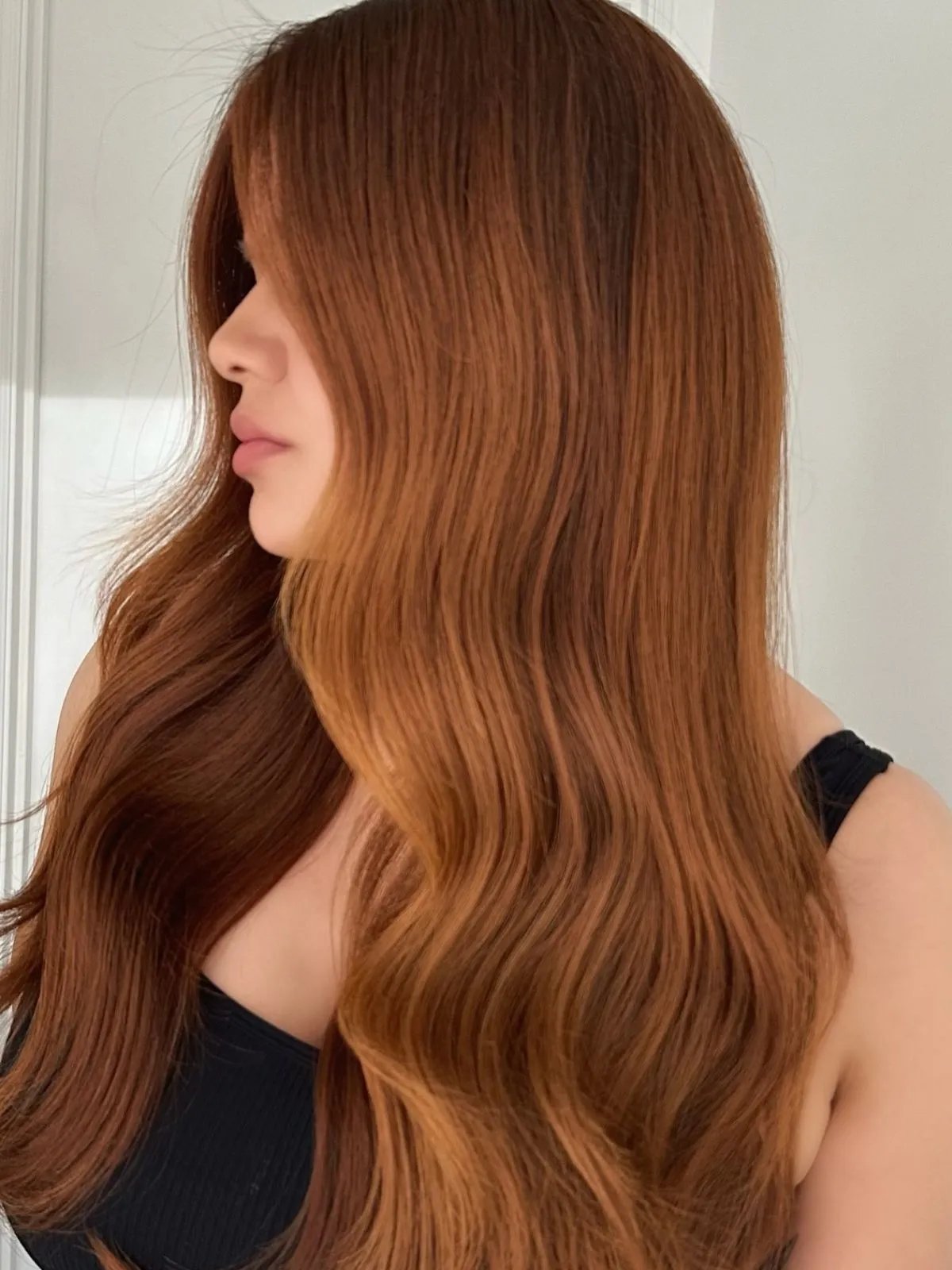 Model with long, brown hair featuring a copper balayage.