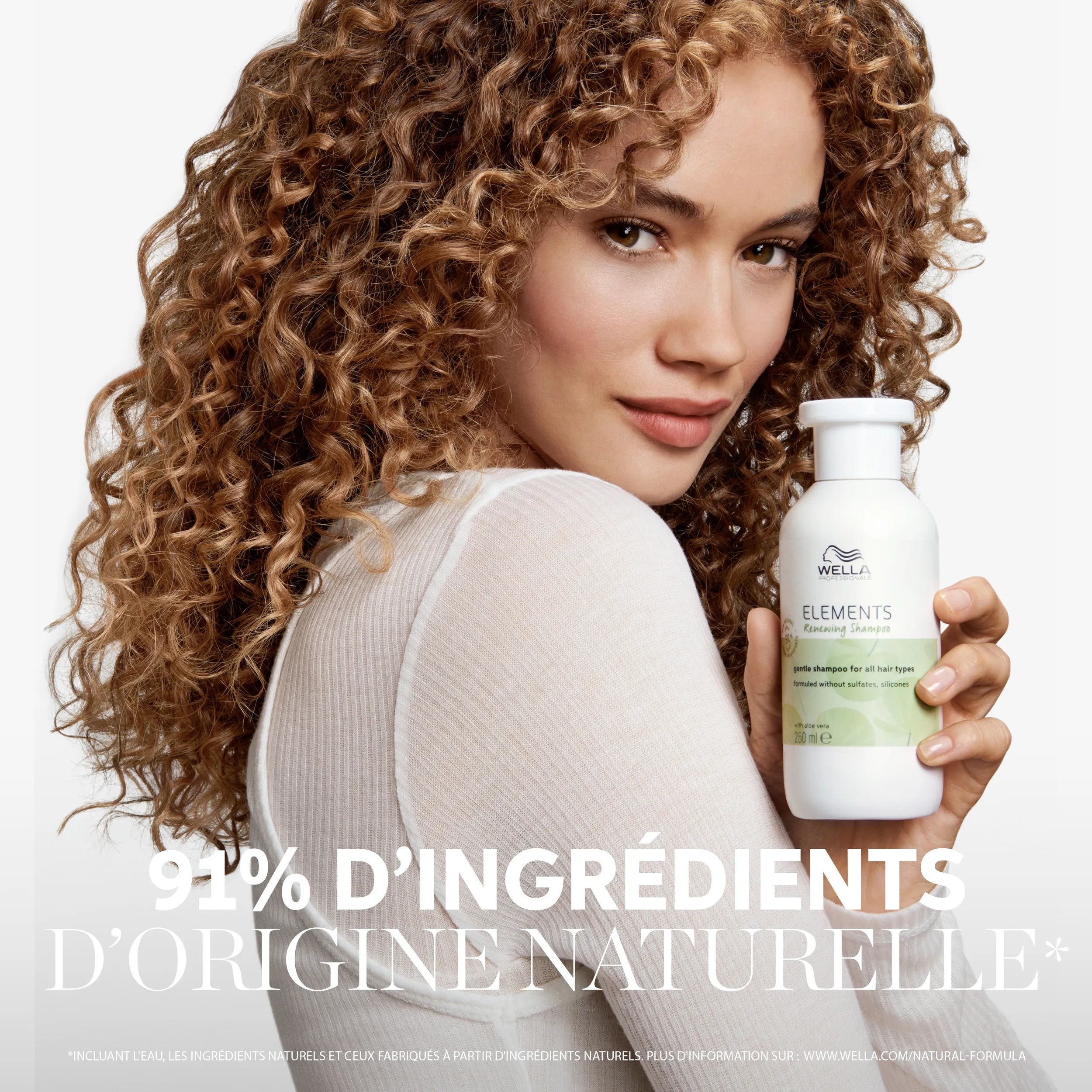 Image d'un jeune modèle féminin aux cheveux bruns bouclés, avec un texte superposé indiquant "Formule d'origine naturelle à 95%* *comprend de l'eau, des ingrédients naturels et des ingrédients fabriqués à partir d'ingrédients naturels. Voir www.wella.com/natural-formula pour plus de détails.'