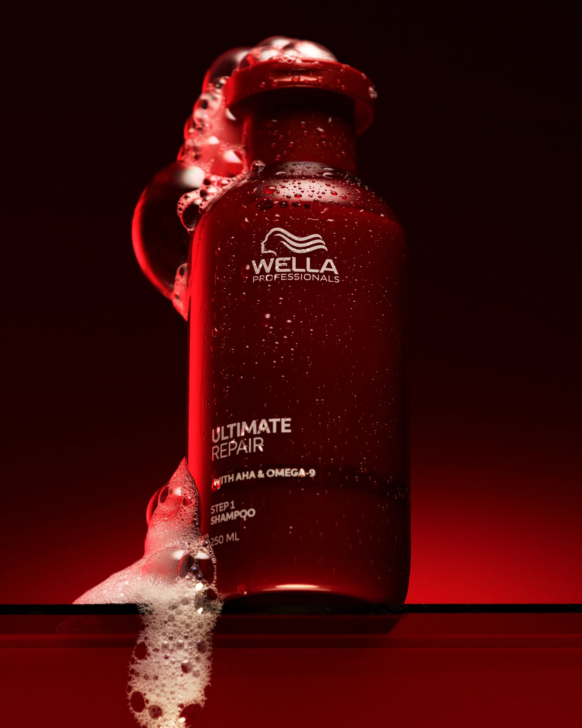 A bottle of Ultimate Repair Shampoo by Wella Professionals over a red background
