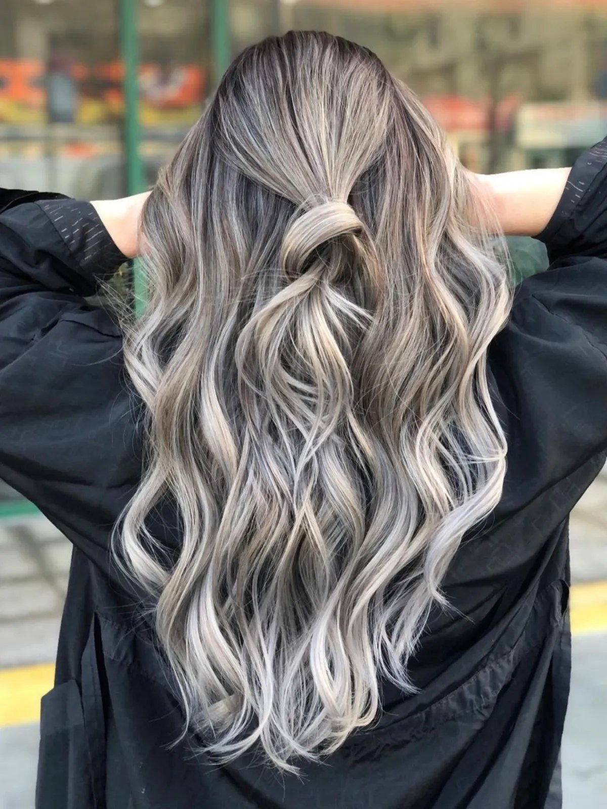 Model with wavy ash blonde hair featuring silver tones through the mid-lengths.