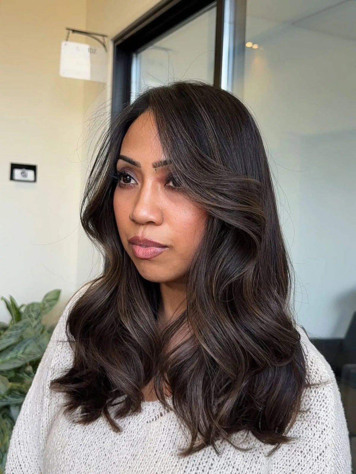 Model with long, loosely curled, espresso brunette hair, featuring subtle highlights. 