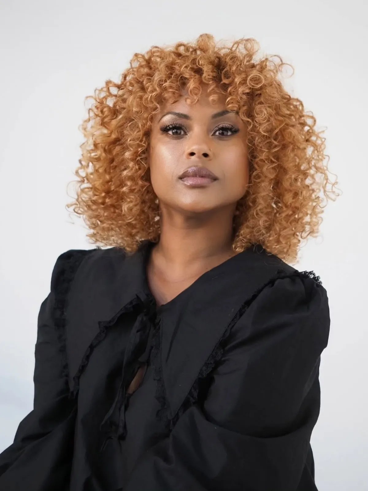 Curly copper honey blonde hair with warm highlights and volume.