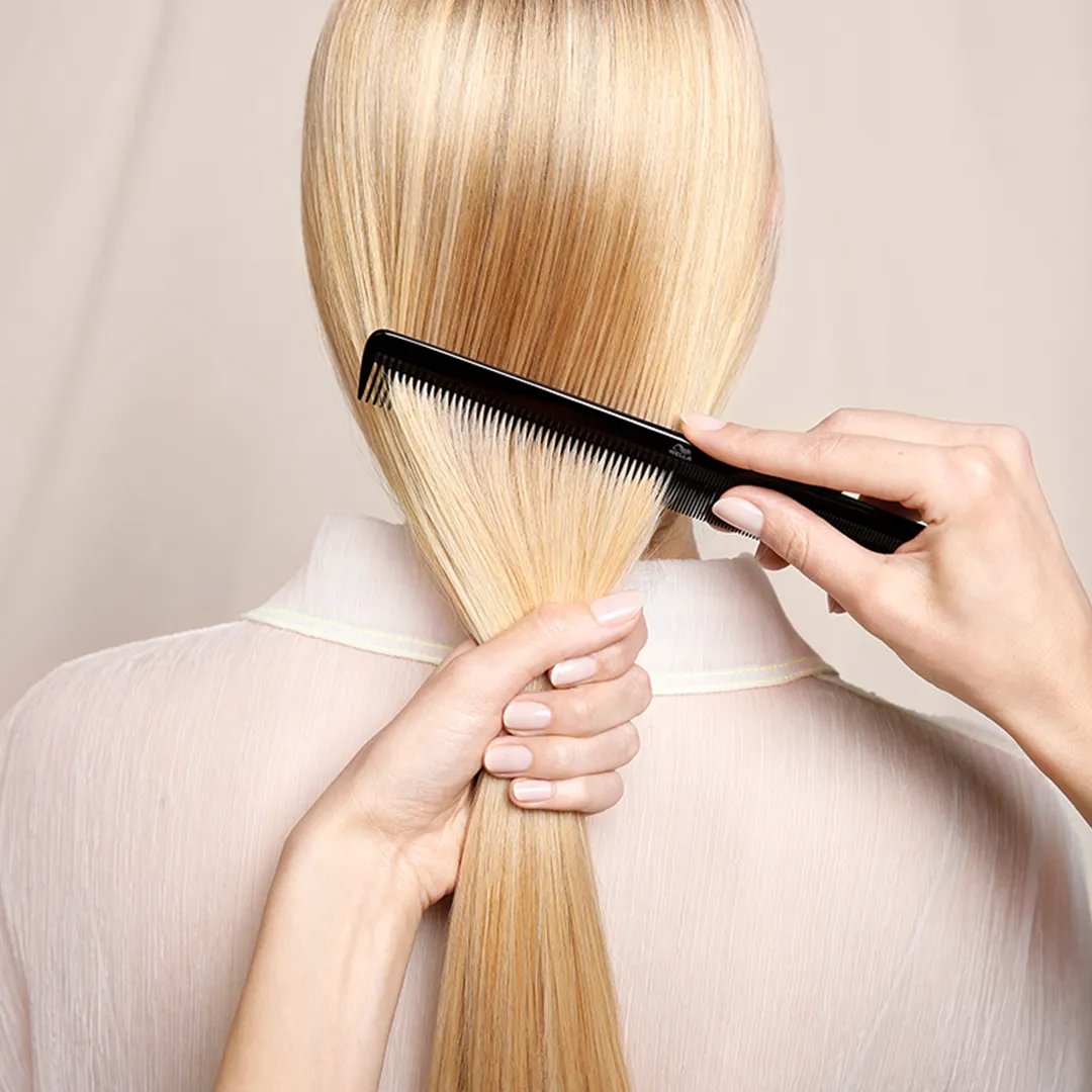 Arrière de la tête d’une femme alors que ses cheveux blonds droits sont peignés.