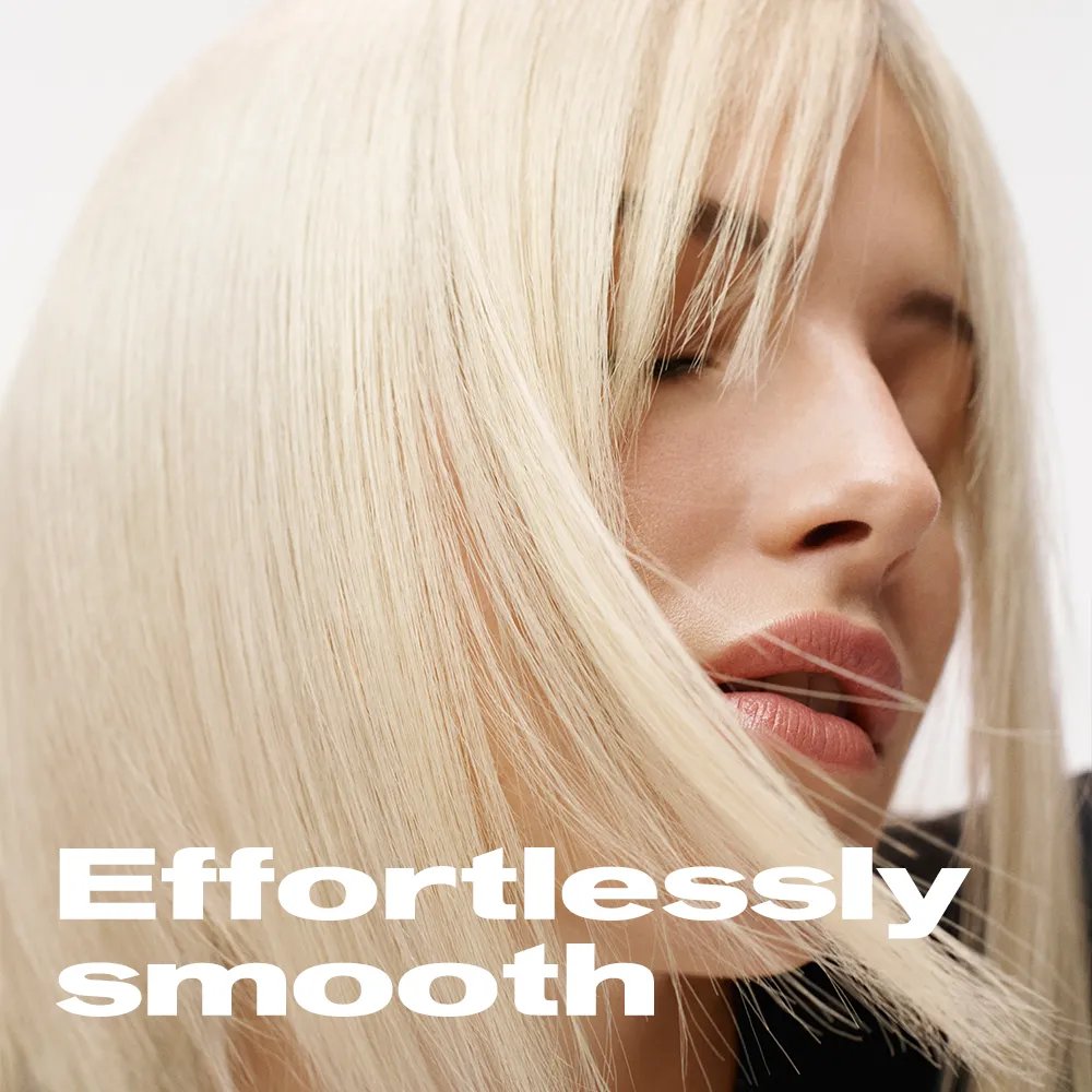 Close up of model turned to the side against white background. Model's hair is covering half of their face. Text overlay states "Effortlessly smooth"