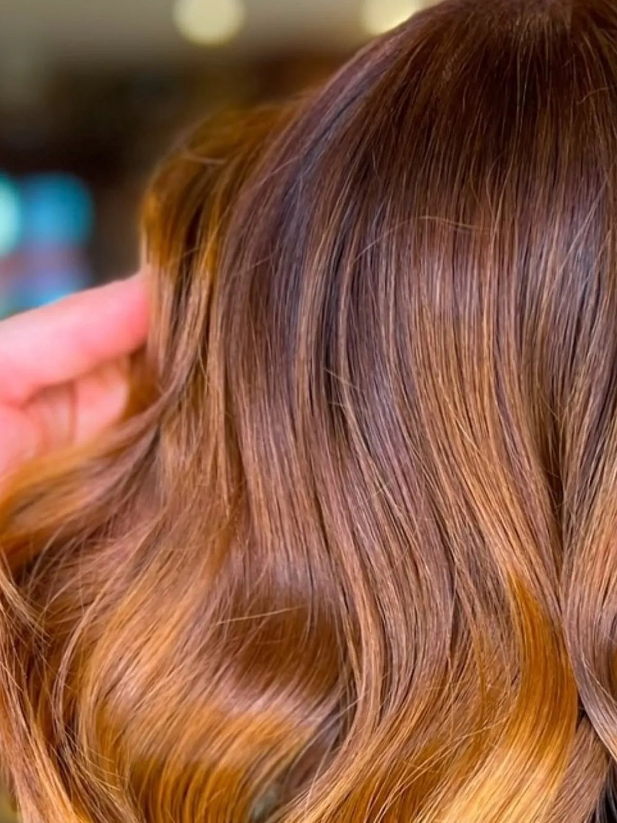 Model with shoulder-length, loosely curled, light copper brown hair.