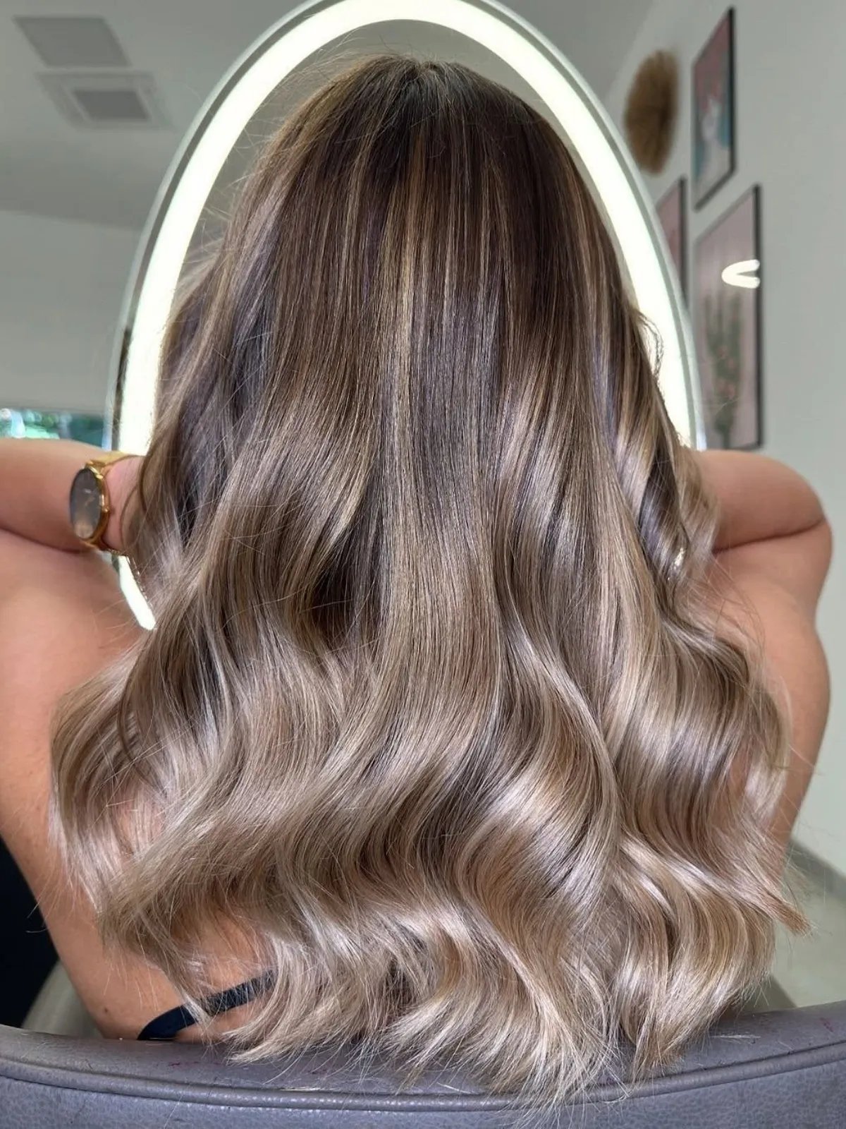 Model with long, loosely curled, ashy brown-blonde hair.