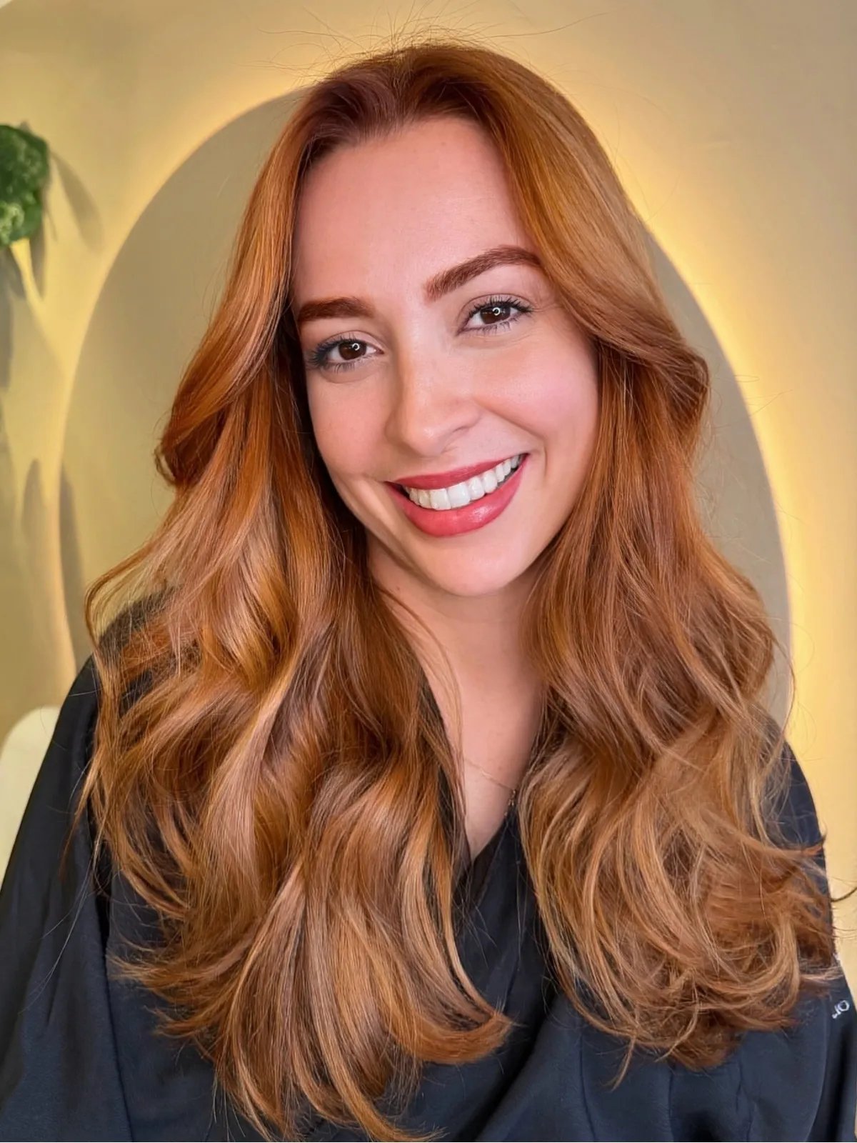 Model with long, loosely curled, copper hair with a honey blonde glow.