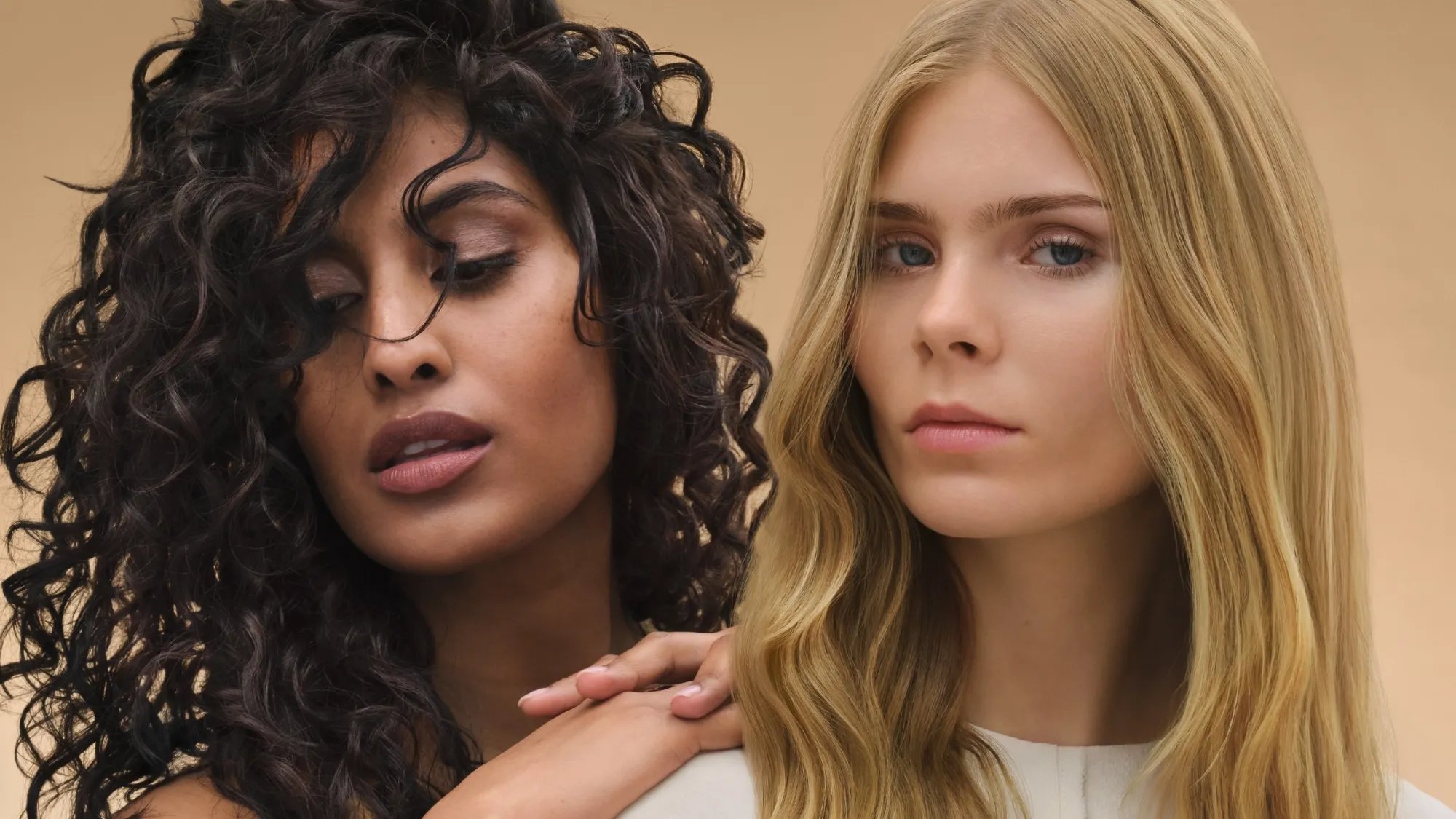 Due modelle – una con capelli castani scuri e ricci e una con capelli biondo miele e lisci.