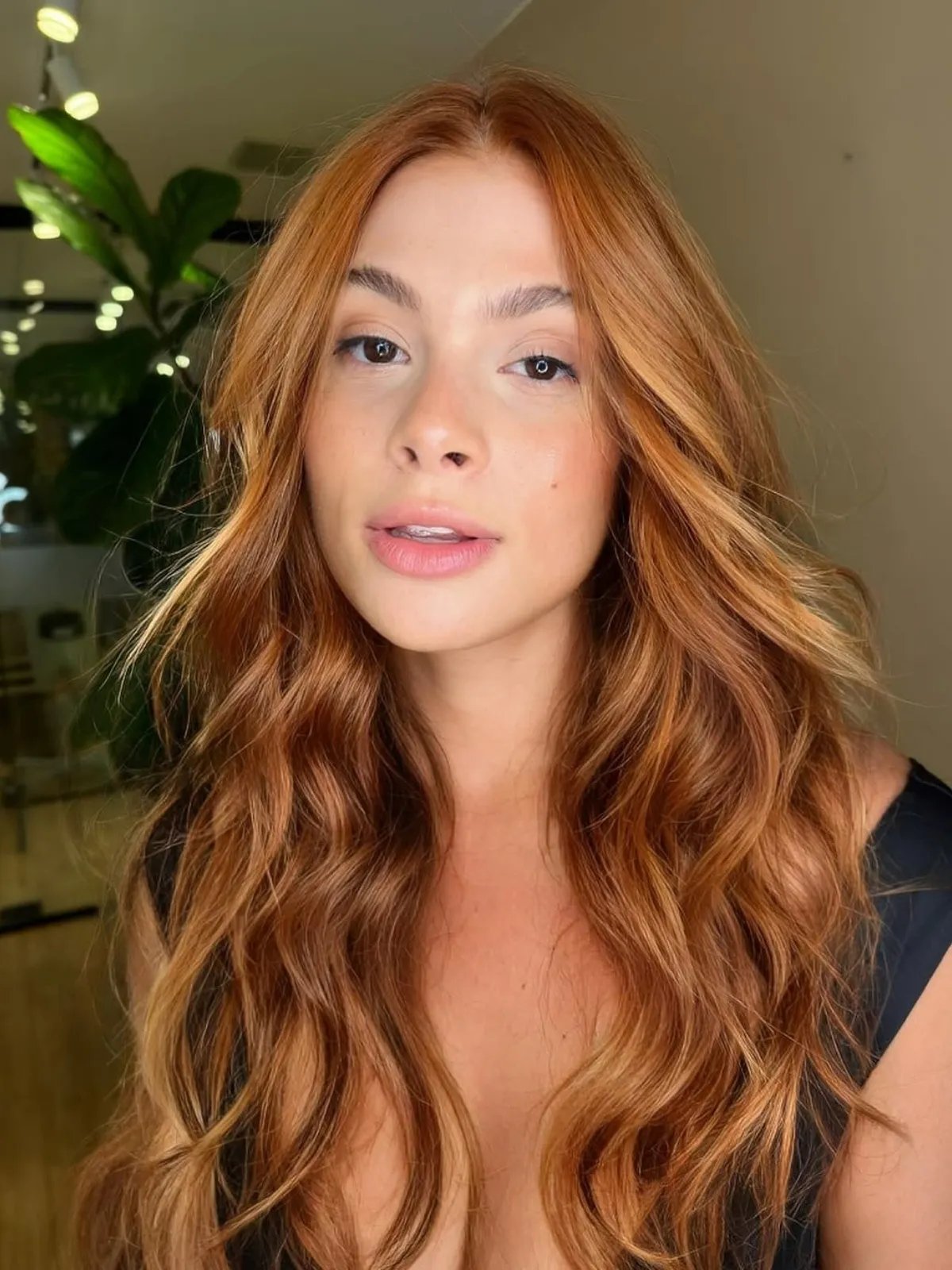 Model with loosely curled, dark strawberry blonde hair.