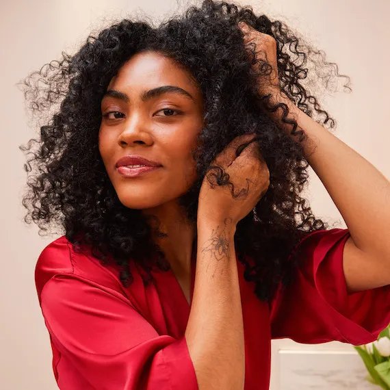 Model with dark, curly hair applies ULTIMATE REPAIR Night Serum.