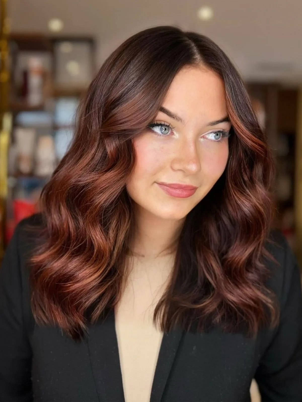 Model with dark brown hair featuring an auburn balayage.