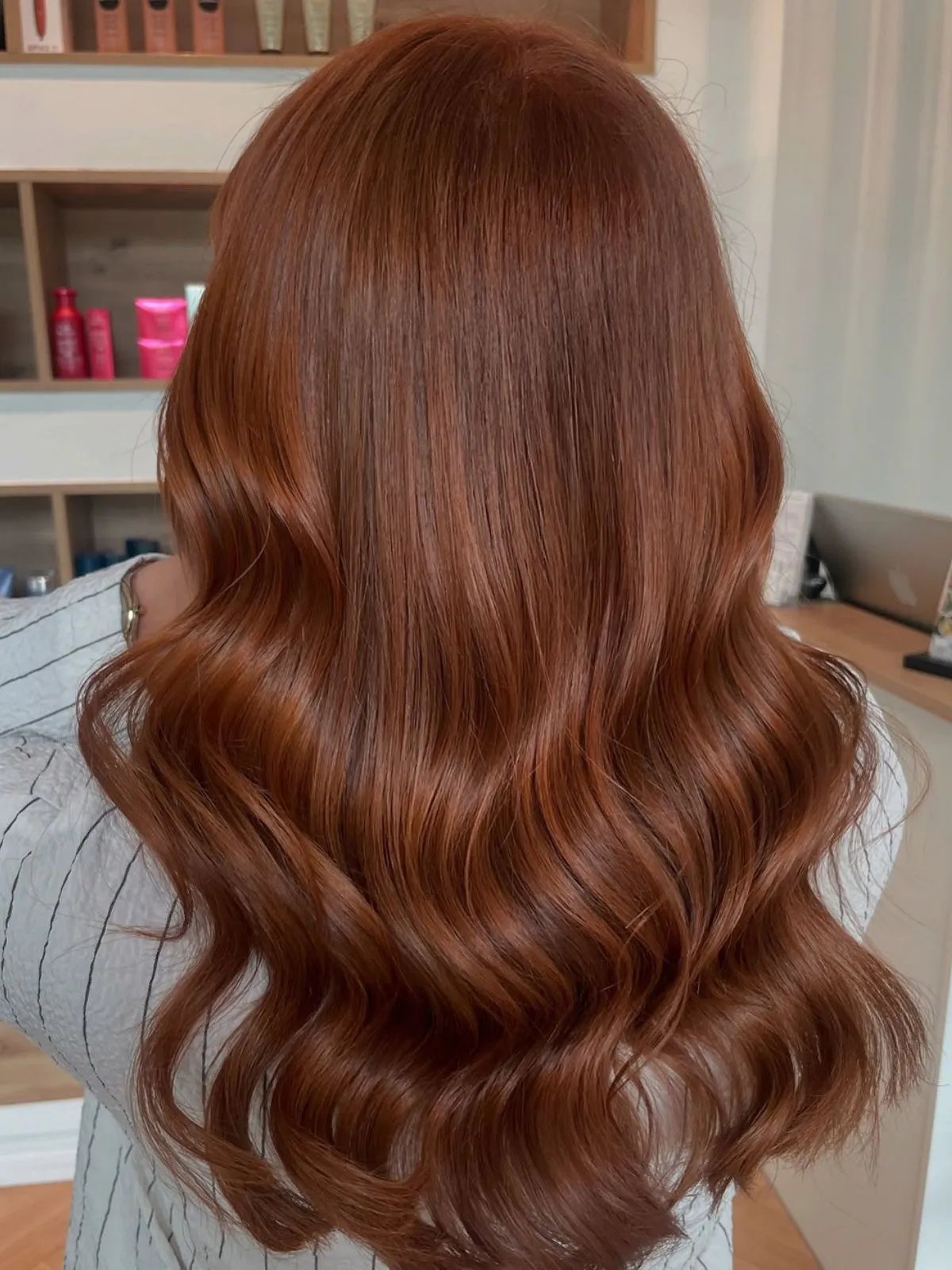 Model with long, loosely curled, light auburn hair.