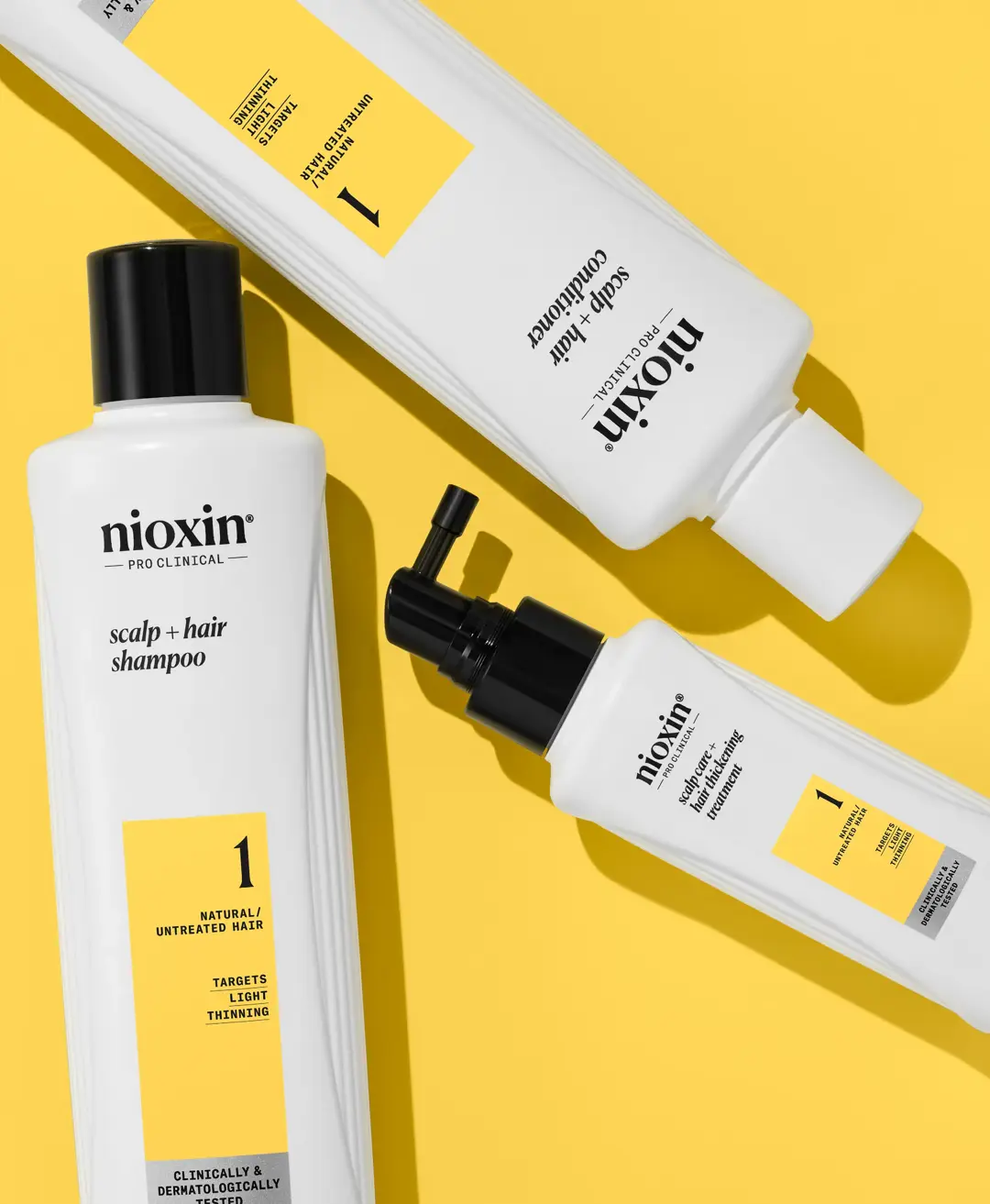 Prodotti del kit di sistema 1 di Nioxin disposti su sfondo giallo