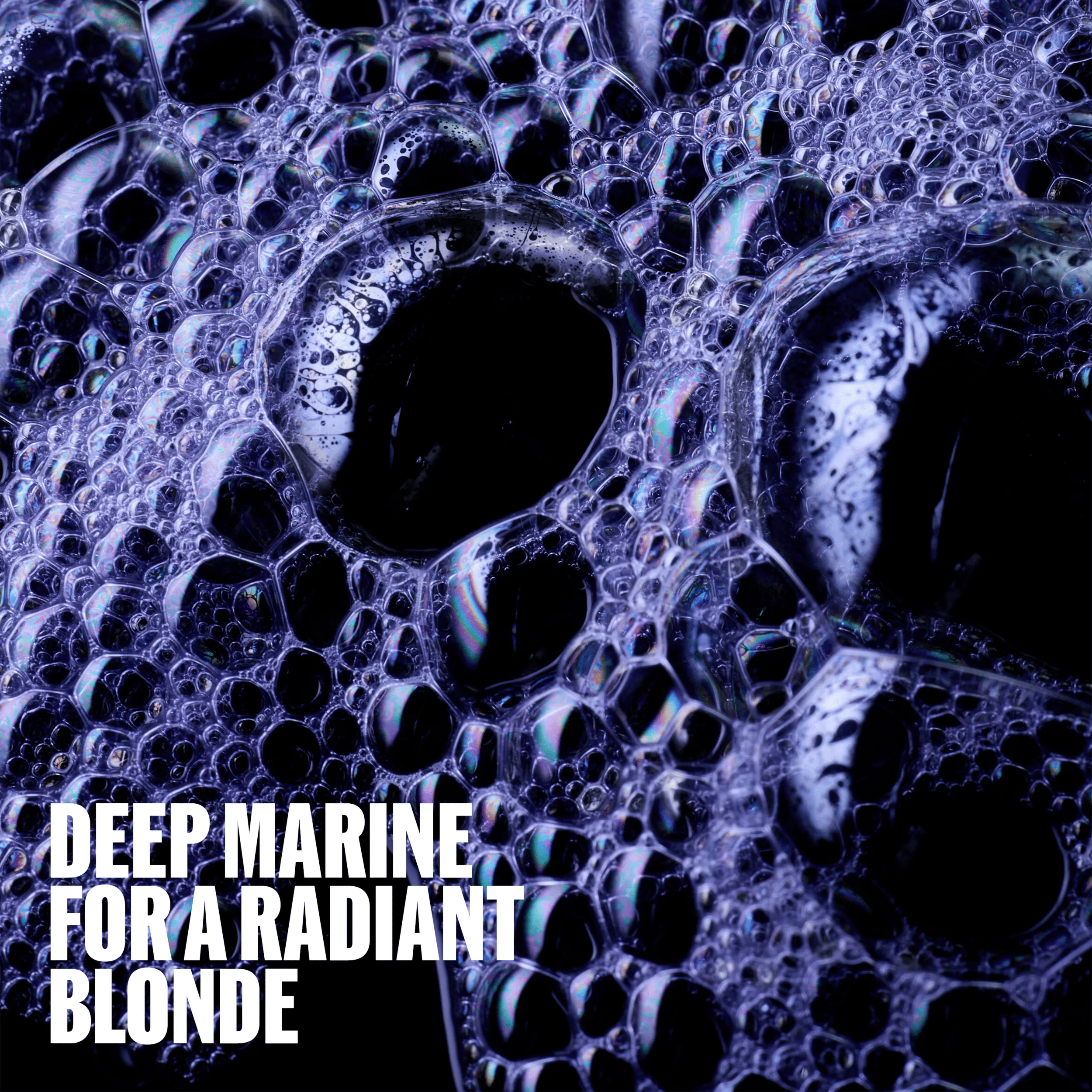 Imagem em grande plano de bolas de sabão contra um fundo roxo escuro. A legenda sobreposta diz: «Deep Marine para uma loira radiante»