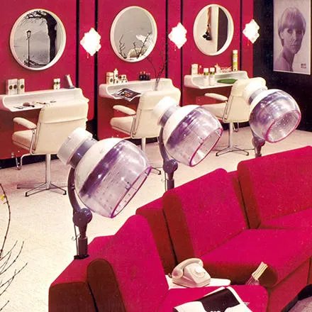 An old fashioned hair salon with a row of heat lamps in the foreground. 