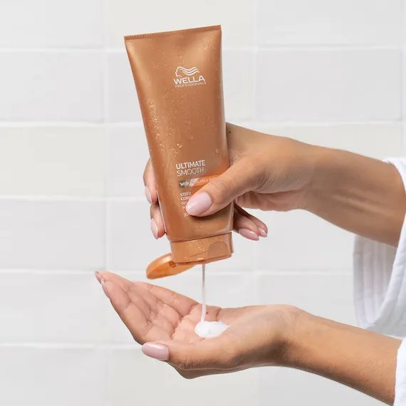 Ultimate smooth conditioner being squeezed into model's hand