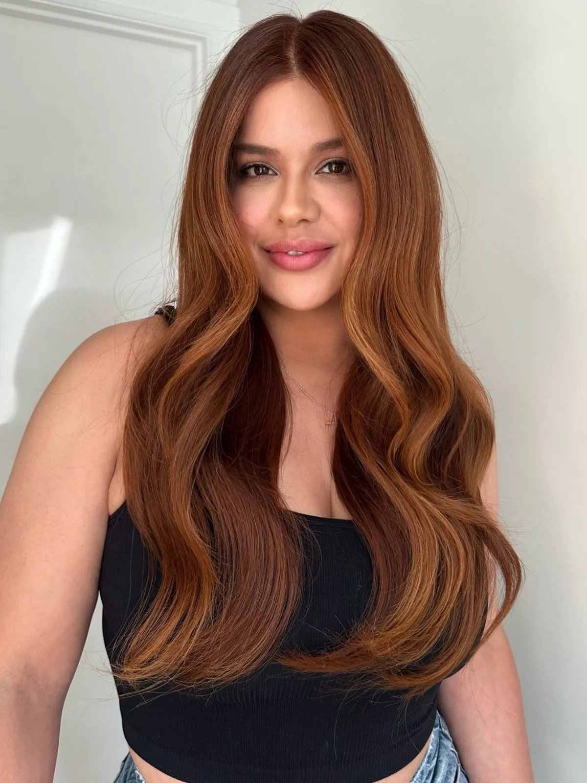 Model with long, brown hair featuring a copper balayage.