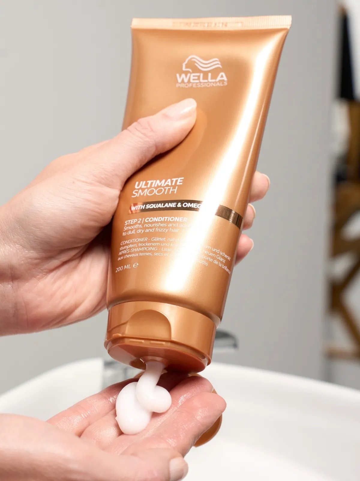 La modella spreme il balsamo ULTIMATE SMOOTH nel palmo della mano.
