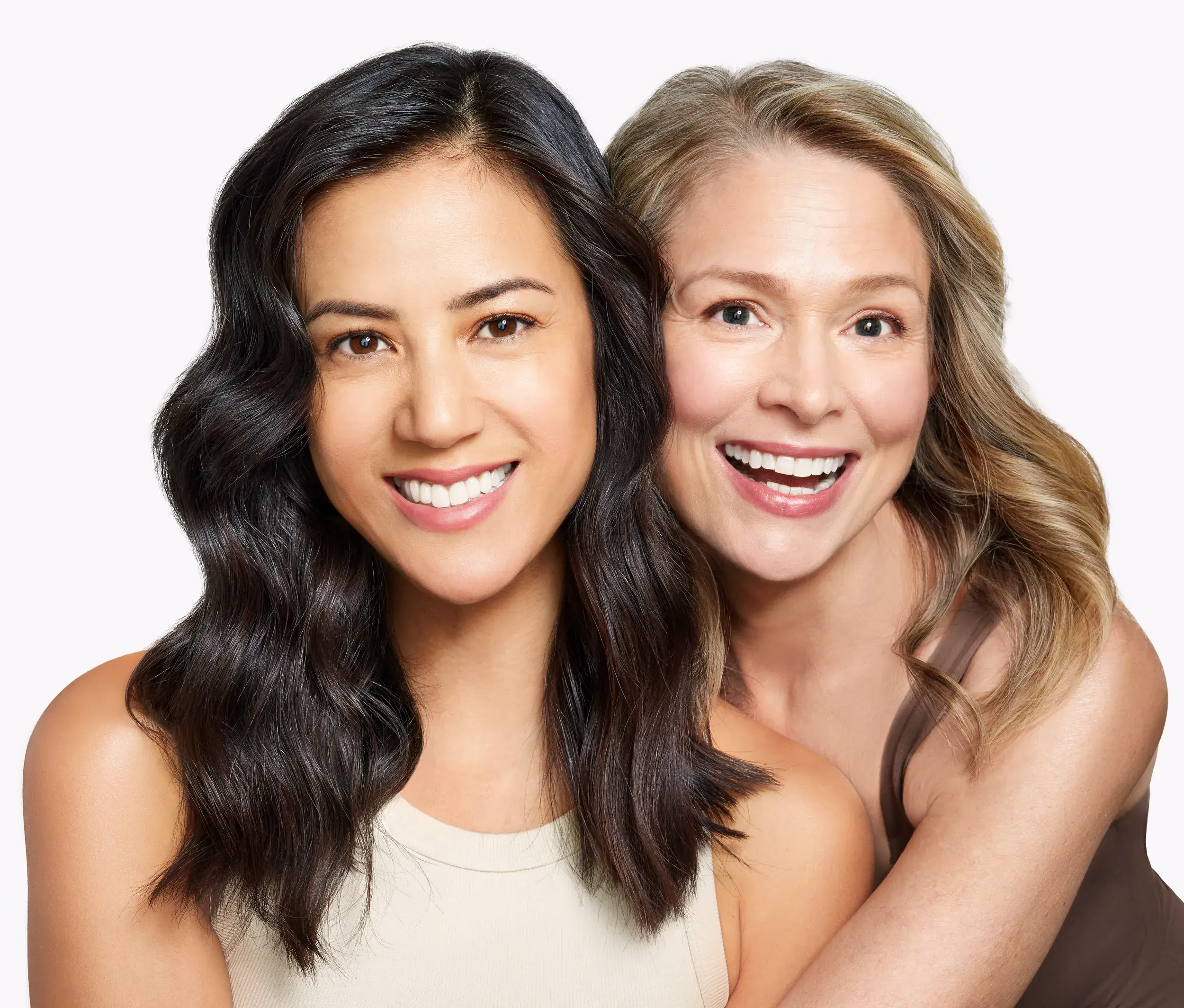 brunette and blonde women smiling against white background