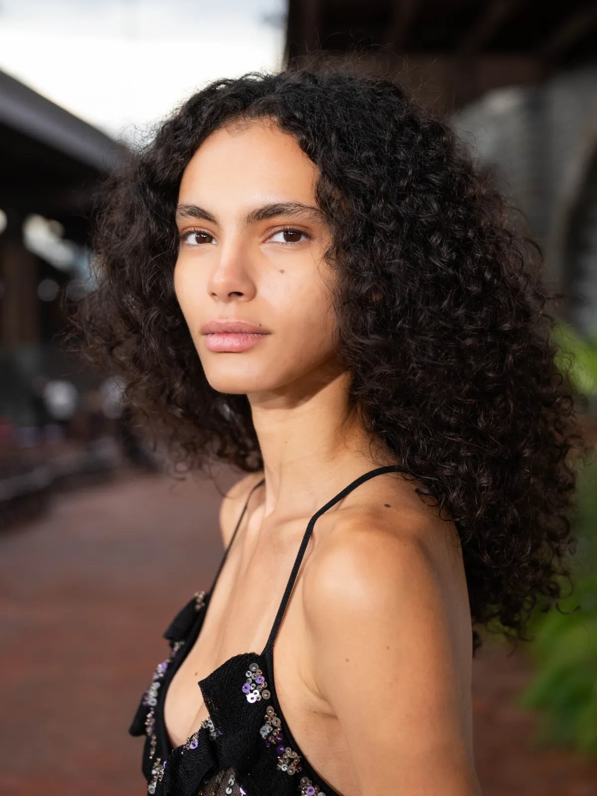 Model with long, dark, curly hair, posing at Ulla Johnson.