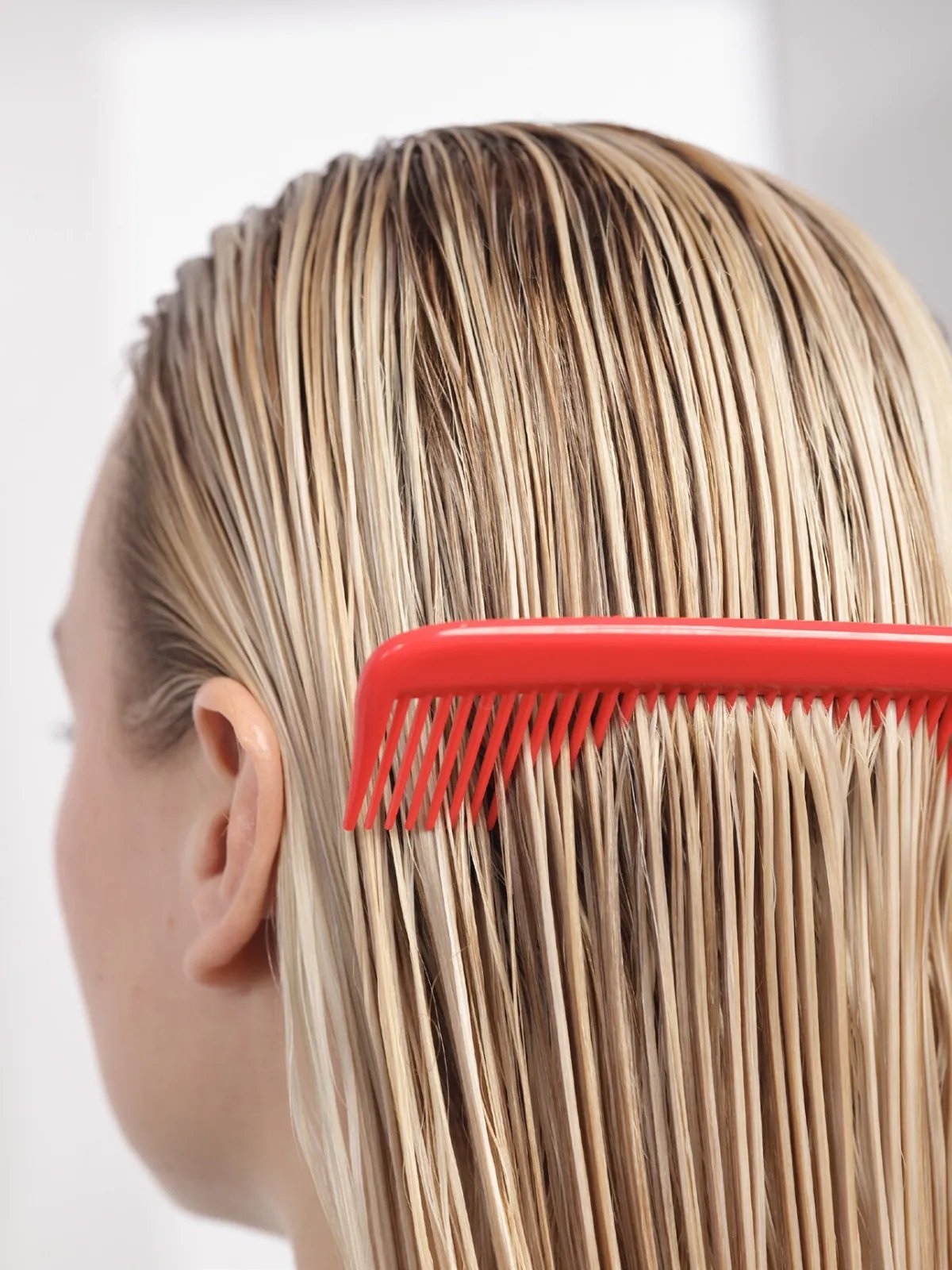 Model runs a red comb through their wet hair.