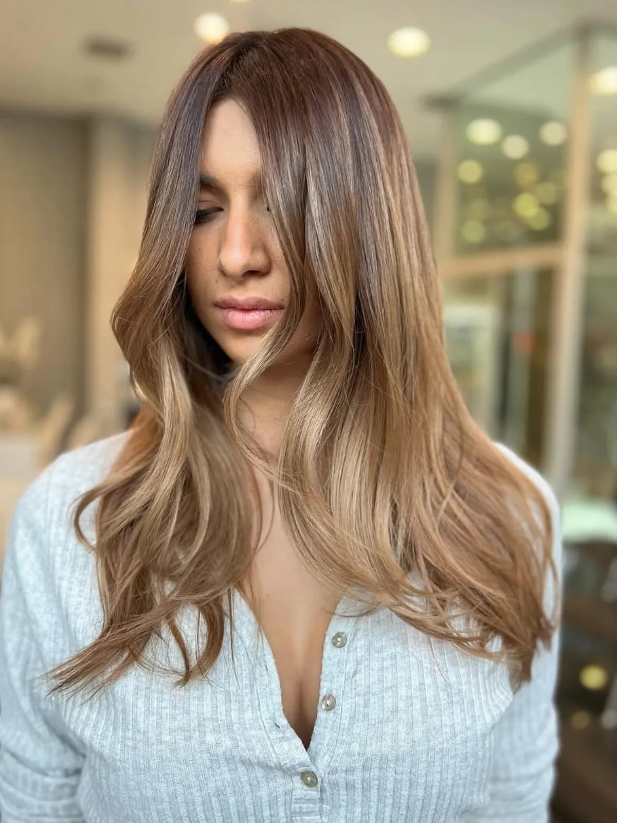 Model with light brown hair and a golden blonde color melt.