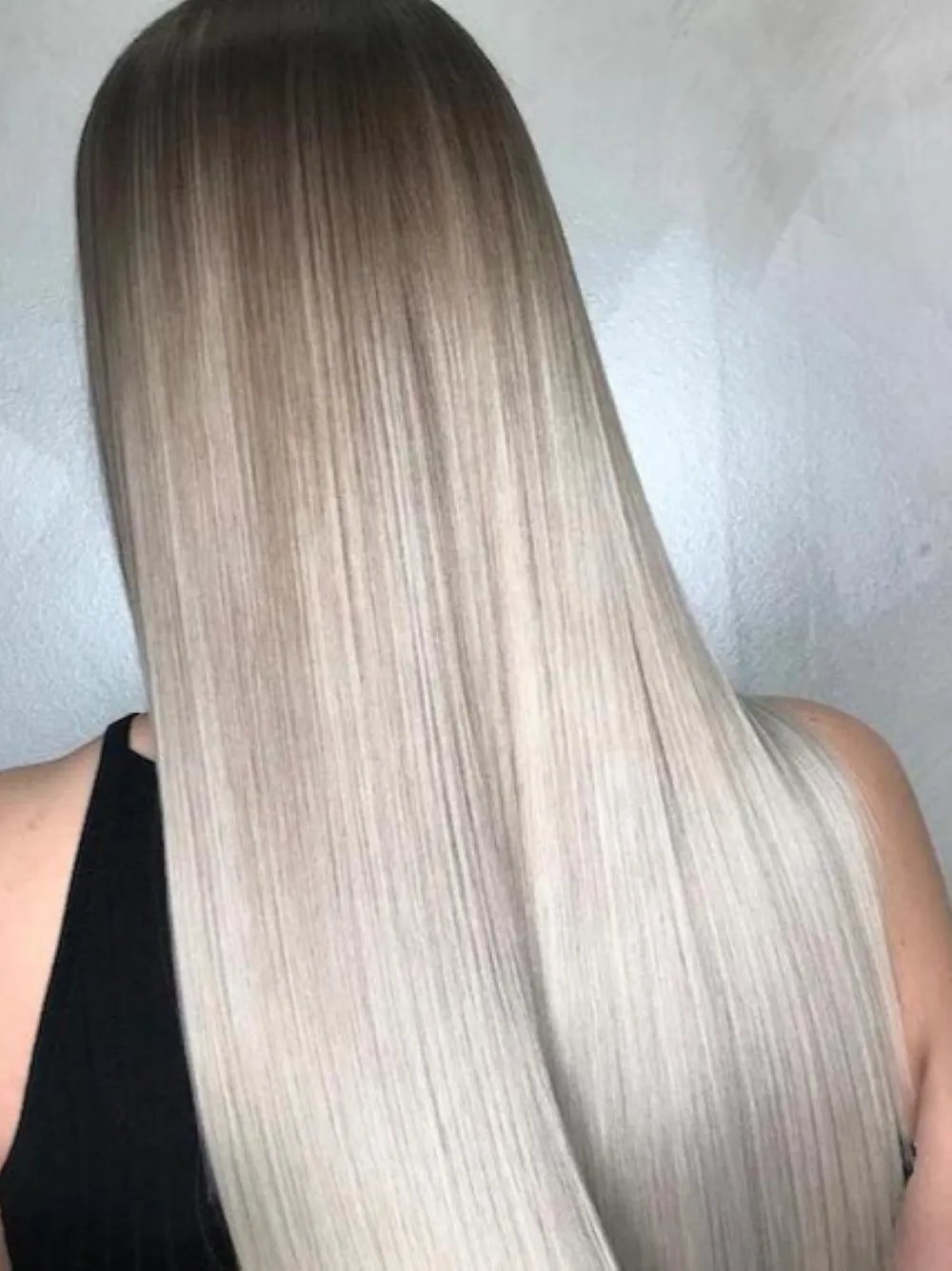 Back view of long, straight hair with dark roots blending into light blonde lengths.