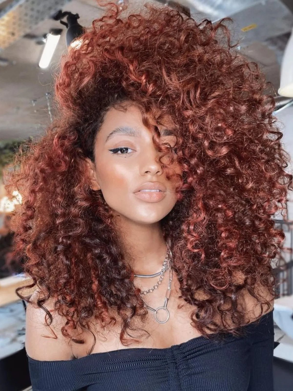 Model with full, voluminous curls in a cowboy copper shade.