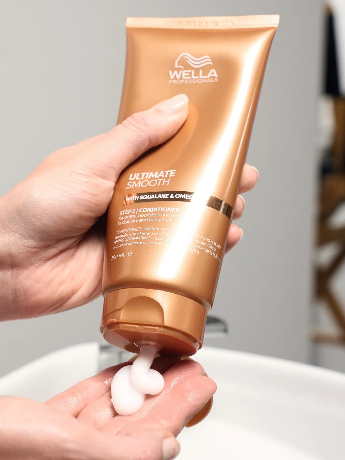 Model squeezes ULTIMATE SMOOTH Conditioner into palm of hand.
