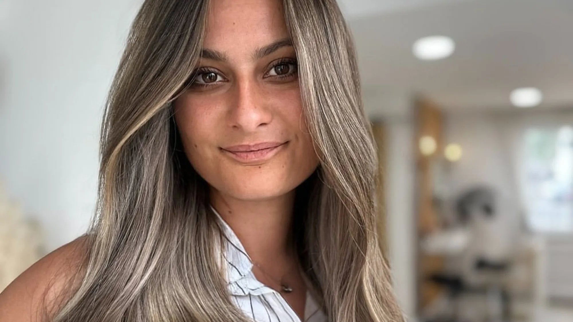 Model with long, loosely waved ash blonde balayage hair.