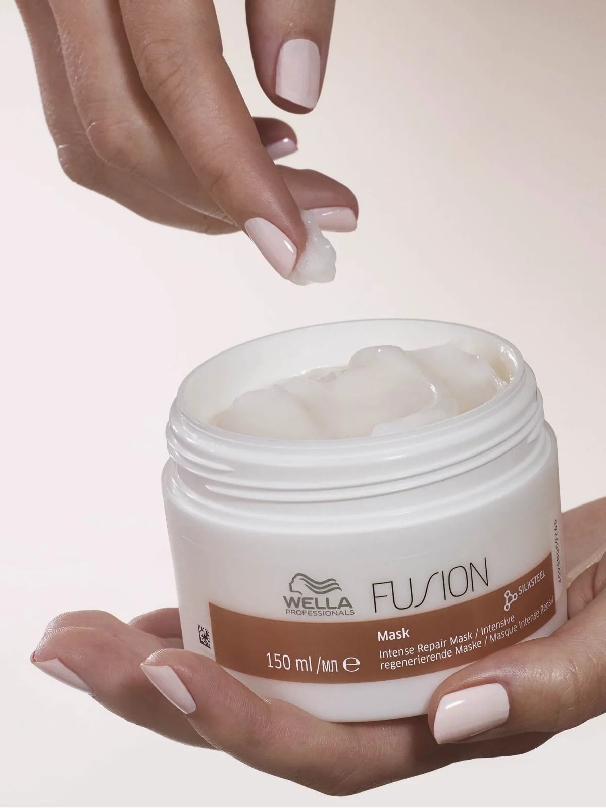 Model’s hand reaches into jar of Fusion Intense Repair Mask.