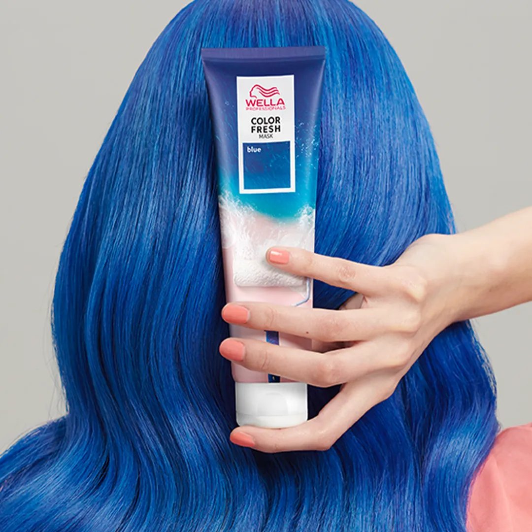 Rückansicht vom Kopf einer Frau mit blauen Haaren, die die Color Fresh Mask in Blau in der Hand hält.