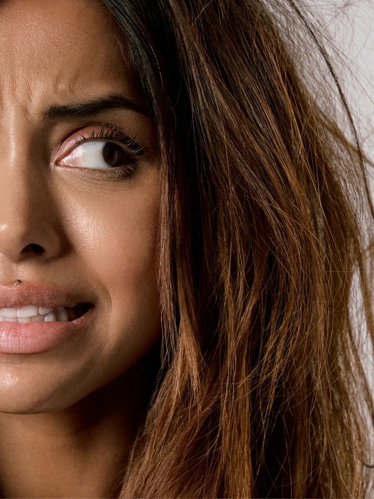 Model looks stressed as they glance at their frizzy hair.