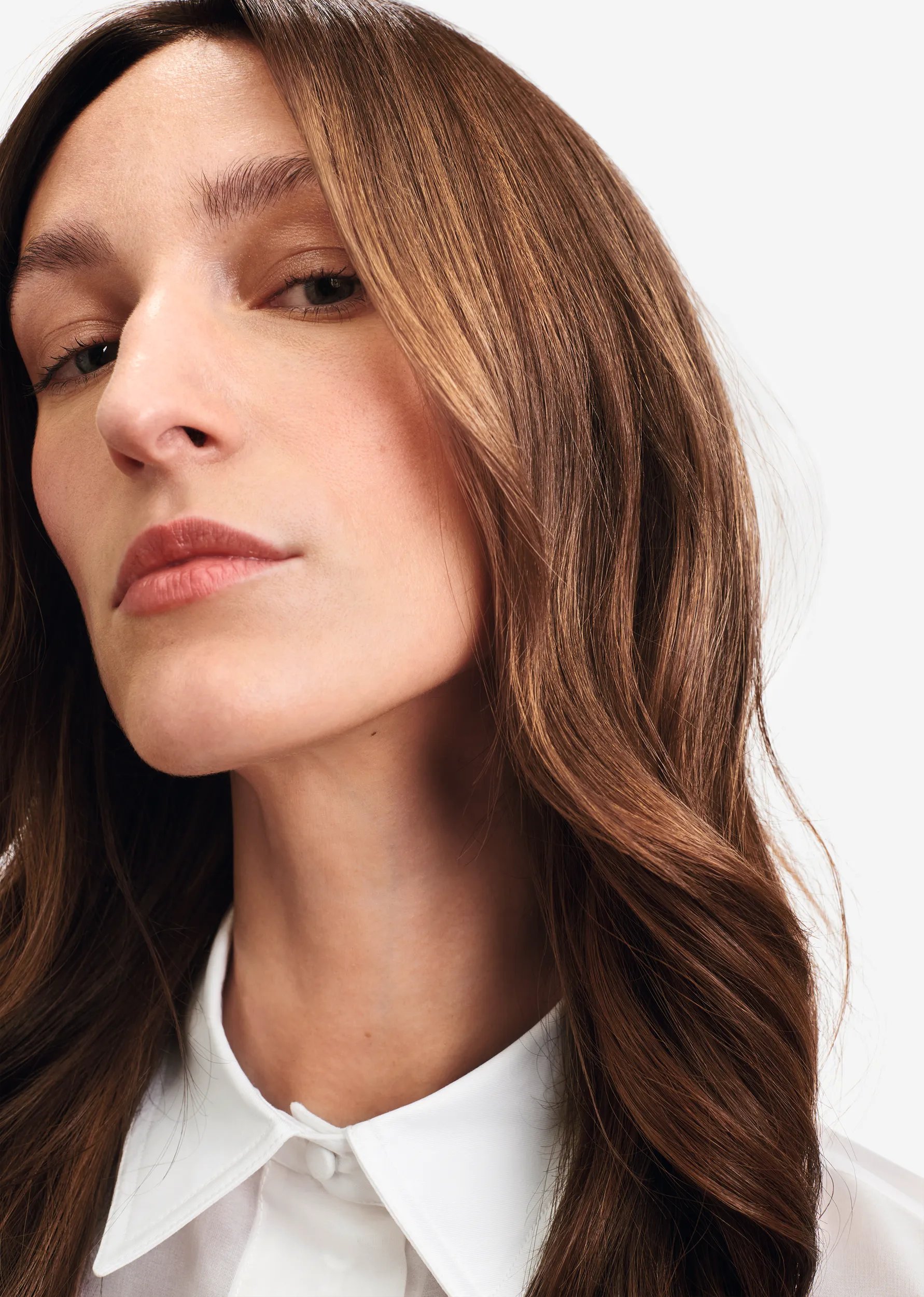 Close up image of model with long, chocolate brown hair looking into the camera.